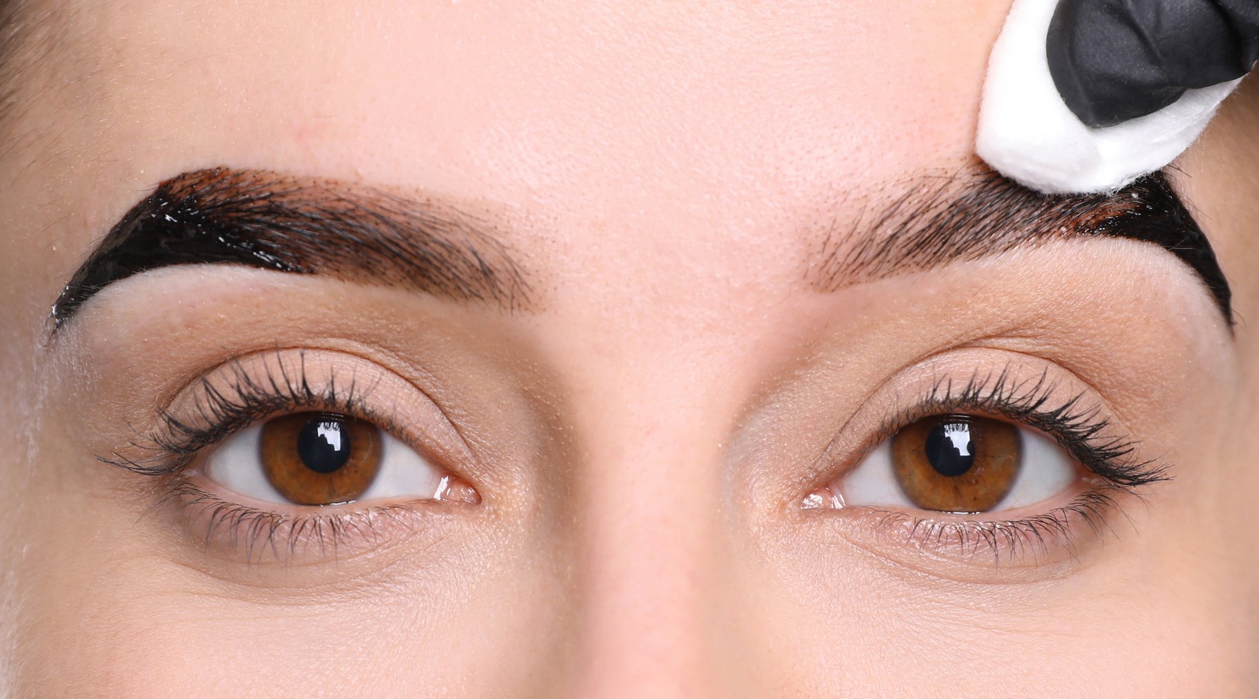 Beautician Wiping Tint from Woman's Eyebrows on White Background